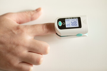 Pulse oximeter on finger showing oxygen saturation and heart rate. Oxymeter.