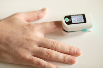 Pulse oximeter on finger showing oxygen saturation and heart rate. Oxymeter.
