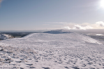 Fototapeta na wymiar View of a path leading over the top of snow covered hill in Scotland on a bright sunny day