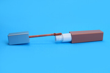 Liquid lipstick with brush on blue background