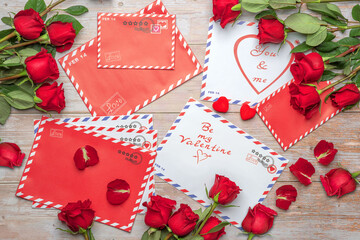 Red roses in bouquets. Letters, mail, craft shopping bag, greetings, valentines, stamps, stars, stripes, circles, hearts, wooden background. The inscriptions "You and me", "Be my Valentine", "love".