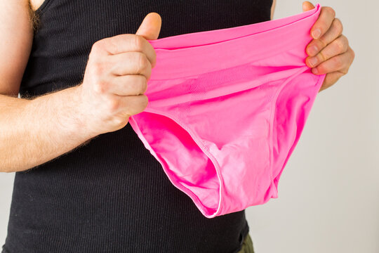 The male type of a man holds pink panties in his hands