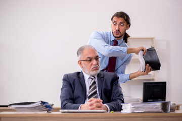 Old male boss and young employee working in the office