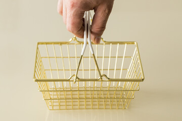 Fototapeta premium An empty golden shopping cart on a cream background