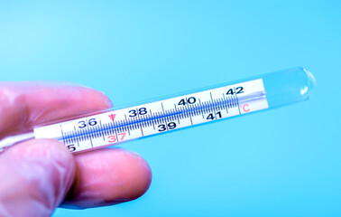 Medical body thermometer in human hands display high temperature.