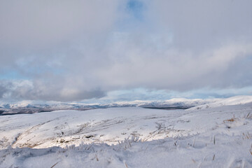Fototapeta na wymiar View of snow covered mountains in the Trossachs National Park from the Ochil Hills in Scotland