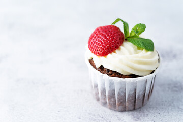 Chocolate cupcakes with cream cheese frosting, mint leaves and strawberries