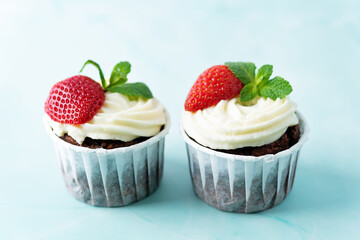 Chocolate cupcakes with cream cheese frosting, mint leaves and strawberries