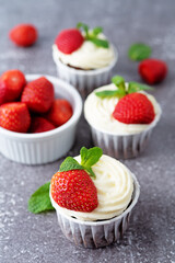 Chocolate cupcakes with cream cheese frosting, mint leaves and strawberries