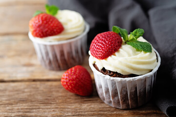 Chocolate cupcakes with cream cheese frosting, mint leaves and strawberries