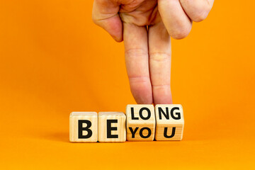 Be you, belong symbol. Businessman hand turns cubes and changes words 'be you' to 'belong'. Beautiful orange background. Business, belonging and be you, belong concept. Copy space.