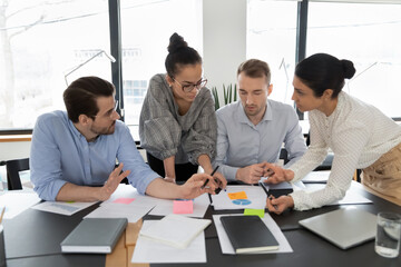 Multiethnic team of colleagues brainstorming over documents, sharing ideas, discussing sales...