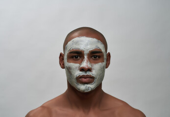 Handsome young african american man looking at camera, using facial blackhead pore removal mask, posing isolated over gray background