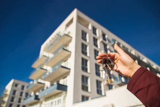 The concept of buying a new apartment. The woman hand holds the keys to a new apartment