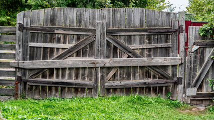 wooden closed gate unpainted with green grass