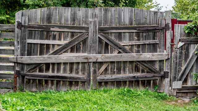 wooden closed gate unpainted with green grass