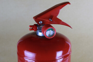 The top of the fire extinguisher, the trigger lever with a safety check and pressure gauge.
