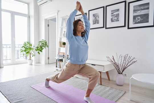 Fit Healthy Young Woman Doing Pilates Yoga Exercise Fitness Training Workout At Home Interior Standing In Warrior Pose. Physical Activity For Body And Mind Relaxation, Healthy Lifestyle Habits Concept