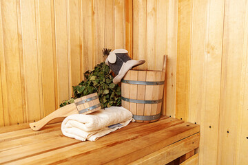Fototapeta na wymiar Interior details Finnish sauna steam room with traditional sauna accessories basin birch broom scoop felt hat towel. Traditional old Russian bathhouse SPA Concept. Relax country village bath concept.