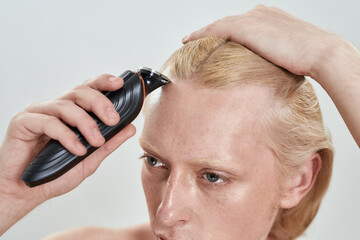 Close up view of trimmer used by young caucasian man