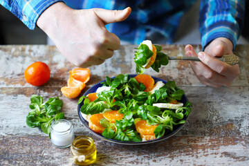 man eats a salad with tangerine and mozzarella. Mash salad Tangerine salad a la caprese.