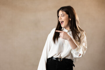 mujer joven morena caucasica señalando a un lado y sonriendo