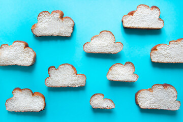 on a blue background, a pattern of cut pieces of a lush cupcake loaf of braided wicker, which are shaped like clouds