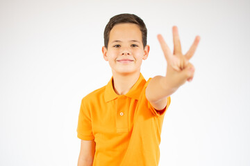 Young little boy kid wearing casual orange t-shirt standing over isolated background showing and pointing up with fingers number three while smiling confident and happy.