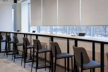 Rows of modern chairs lined up, a long wooden table, a place for charging gadgets and meetings