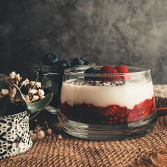 CREAMY YOGURT WITH RASPBERRIES AND BLUEBERRIES ON A DARK BACKGROUND