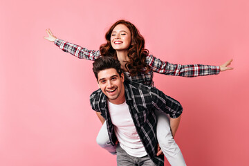 Excited girl in checkered shirt having fun with boyfriend. Young couple celebrating valentine's day.