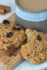 Close-up on oatmeal and raisins whole wheat cookies, spices and coffee with half and half on bamboo serving tray against blue background – comfort food side view