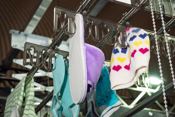 A hanger with things in the dry cleaners. Linen is dried after washing. Clean clothes in the laundry room. Professional cleaning of clothes and home shoes. Business on dry cleaning services.