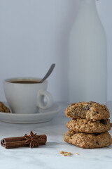Oatmeal raisin cookies, spices and cofee with milk on white