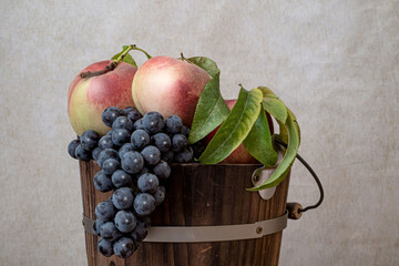 Top of a bucket made of wood and filled with peaches and comstock grapes: still life celebrating the California summer harvest