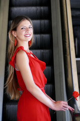 Giovane donna con vestito rosso su scala mobile