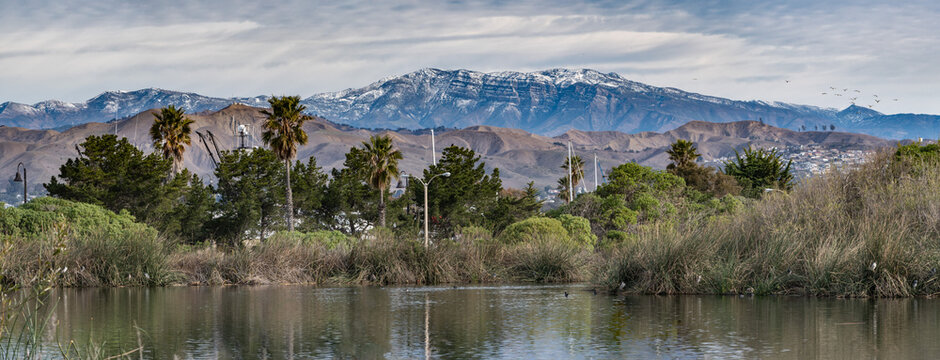 Compressed landscape view of coastal esturary pond in foreground looking across Ventura to snow covered mountains of Topatopa in distance. © motionshooter