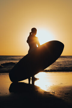 surfer preparing to surf in the beach at sunset