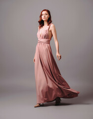 Bridesmaid's look in dust pink. Young ginger woman in summer transformer evening dress and high...