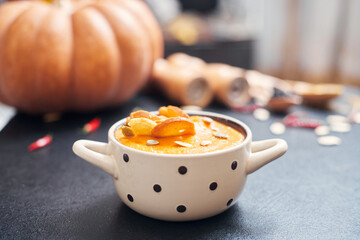 pumpkin cream soup with croutons on a black table with spices