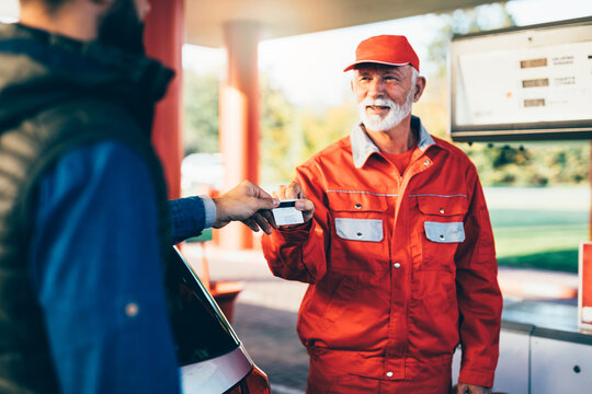 Young man using credit card to make a payment for refueling car on gas station.