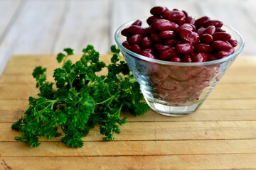 Red Kidney beans in glass bowl with fresh herbs ready for preparing healthy vegan or vegetarian meals. Simple bowl of beans photo concept with copy space