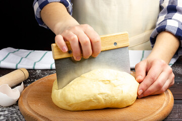 The process of making yeast dough for baking bread. The woman cuts the pastry into pieces.
