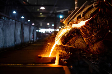 Casting, melting, molding and foundry. Bucket with hot molten iron pouring into the mold....