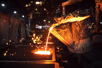 Molten metal casting in foundry. Filling mold with hot liquid iron and producing iron components in steel plant. - obrazy, fototapety, plakaty