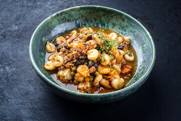 Modern style traditional slow cooked Mexican pozole rojo soup with ground minced beef, hominy maiz and beans served as close-up in a Nordic design plate