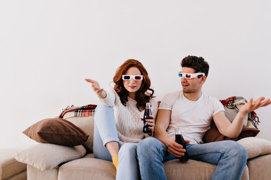 Couple with glass bottles watching movie. Woman and man enjoying 3d film in valentine's day.