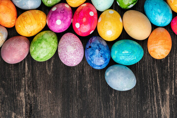 Different easter eggs on wooden plate on green table