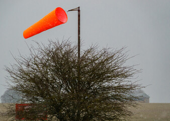 bright orange airfield wind sock billowing in strong winds and snow, winter on Salisbury Plain