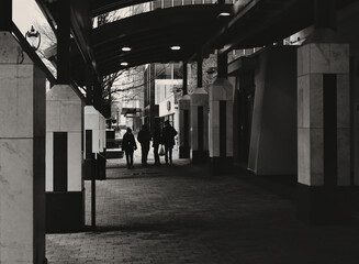 A group of people walking down a shadowy city sidewalk colonnade in Raleigh, North Carolina. Copy space.
